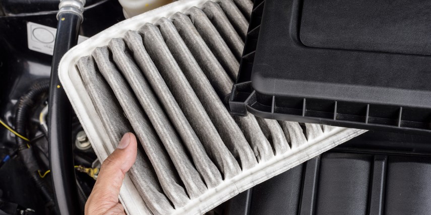 A mechanic pulls the air filter from the case on a diesel truck to see if it needs cleaning.