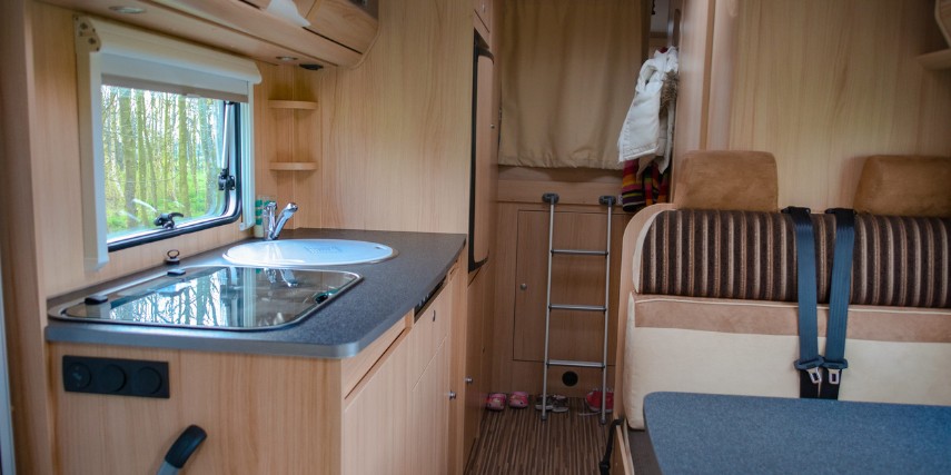 Interior of a used RV, showing kitchen and seating area.